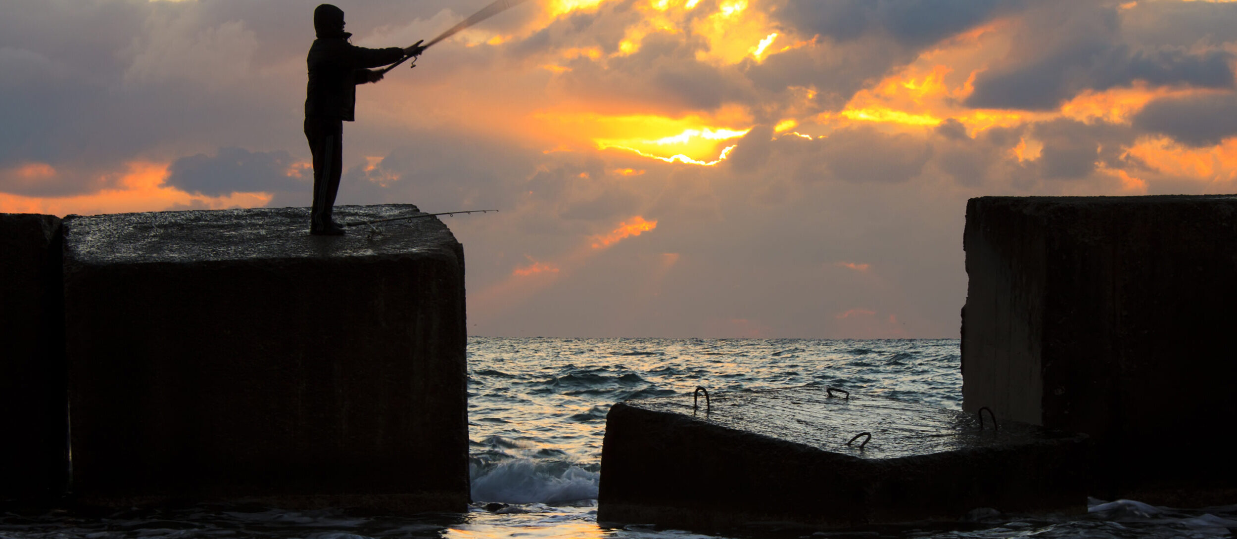Fisherman on pier at sunset